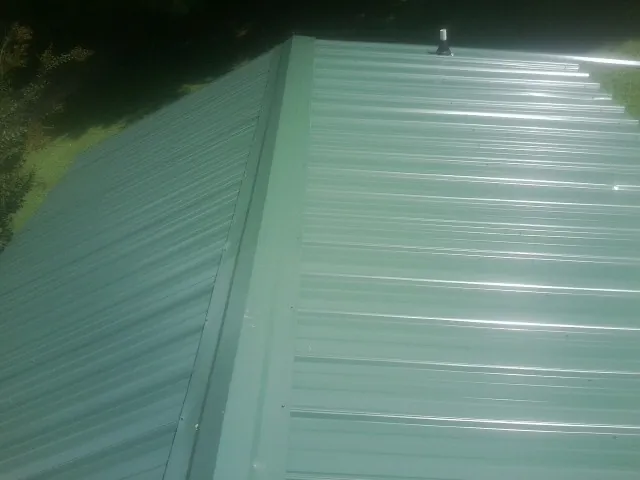 New green metal panels meeting at the ridge of a roof — Flat Roof Repair work by our crew in Baring