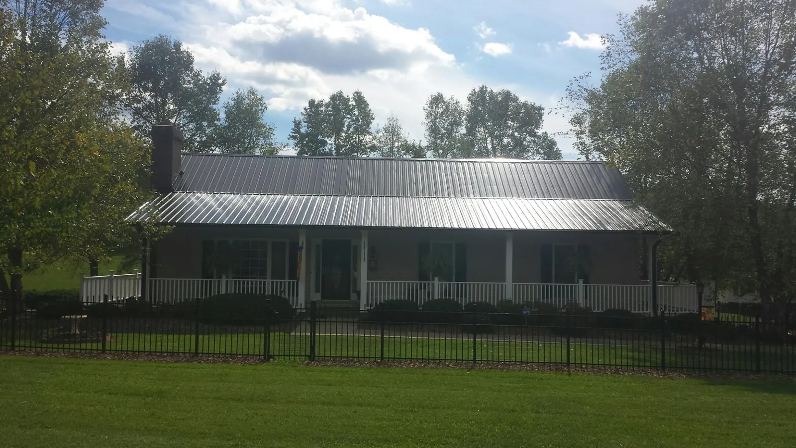 Gray metal roof on a brick ranch with a full width front porch — Gutter Guard Installation work by our crew in Baring