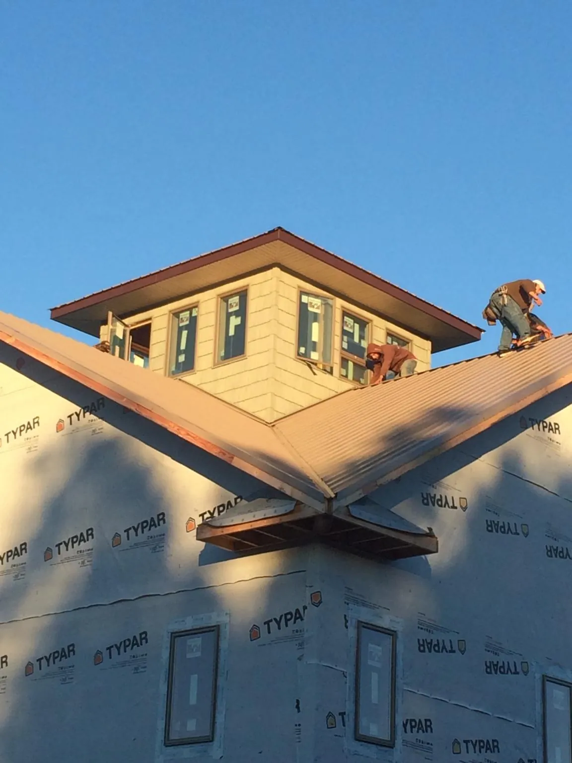 Roofers working around a rooftop cupola on a new metal roof at sunset — Roof Waterproofing in Baring by Roofing Brothers